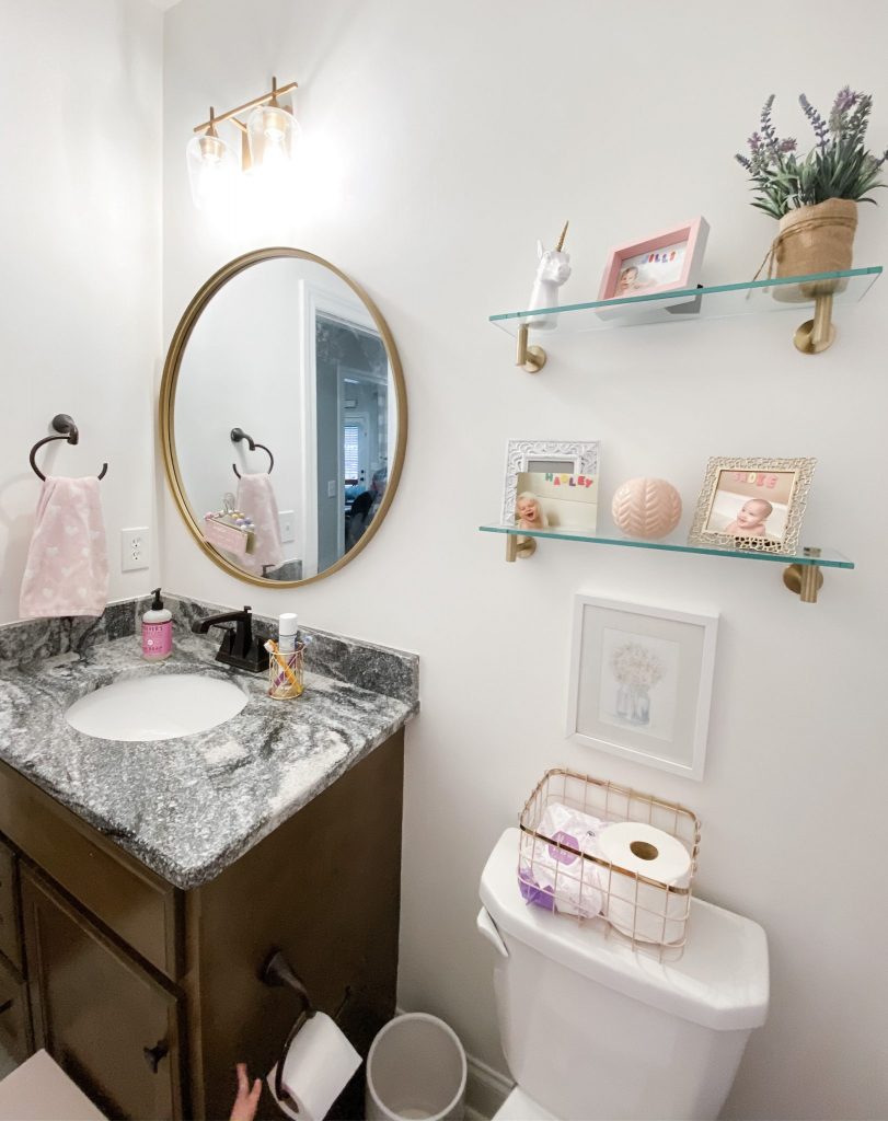 Hall Bathroom Makeover for little girls: This hallway full bathroom follows a white, gold, and pastel color scheme and was completed for less than $600. All sources included for the mirror, light fixture, shelves, shower curtain, shower curtain liner, bath mat, towels, bath hooks, and more. Enjoy!